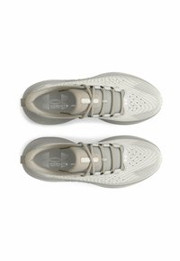Des chaussures de sport gris clair présentent une tige en maille, un design texturé, un bout rond et des lacets plats. La marque est visible sur la languette et la semelle intérieure.