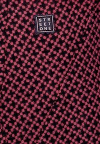 Tyg i ullblandning med ett svart och rosa rutmönster. Har en rektangulär marinblå etikett med vit text "STREET ONE". Mjuk textur.