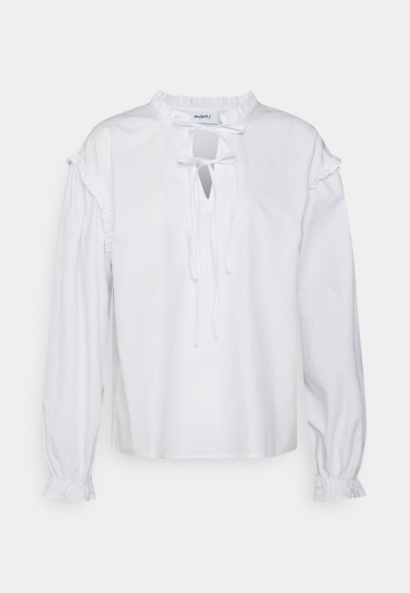 Blusa branca de mangas longas com decote arredondado, detalhes franzidos nos ombros e um fechamento com laço na parte da frente. Textura de algodão suave.