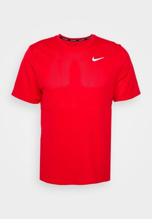 Punainen Nike lyhythihainen urheilupaita, jossa on verkkokuidusta valmistetut paneelit rinnassa ja valkoinen Nike Swoosh -logo ylävasemmalla.