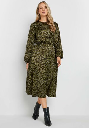 Vestito verde con stampa leopardata, maniche lunghe, vita arricciata e gonna fluida. Abbinato a stivaletti neri alla caviglia. Tessuto morbido e leggero.