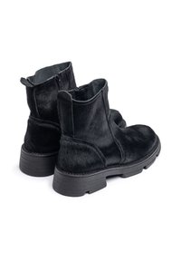 Botines de piel sintética negra con un acabado texturizado, puntera redonda y suela de goma plana. Presentan un cierre de cremallera en la parte posterior.