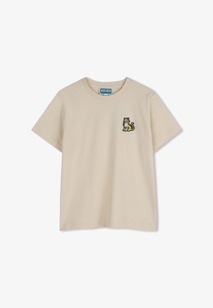 T-shirt color beige in cotone con maniche corte, caratterizzata da un piccolo motivo ricamato a forma di tigre sul lato sinistro del petto.