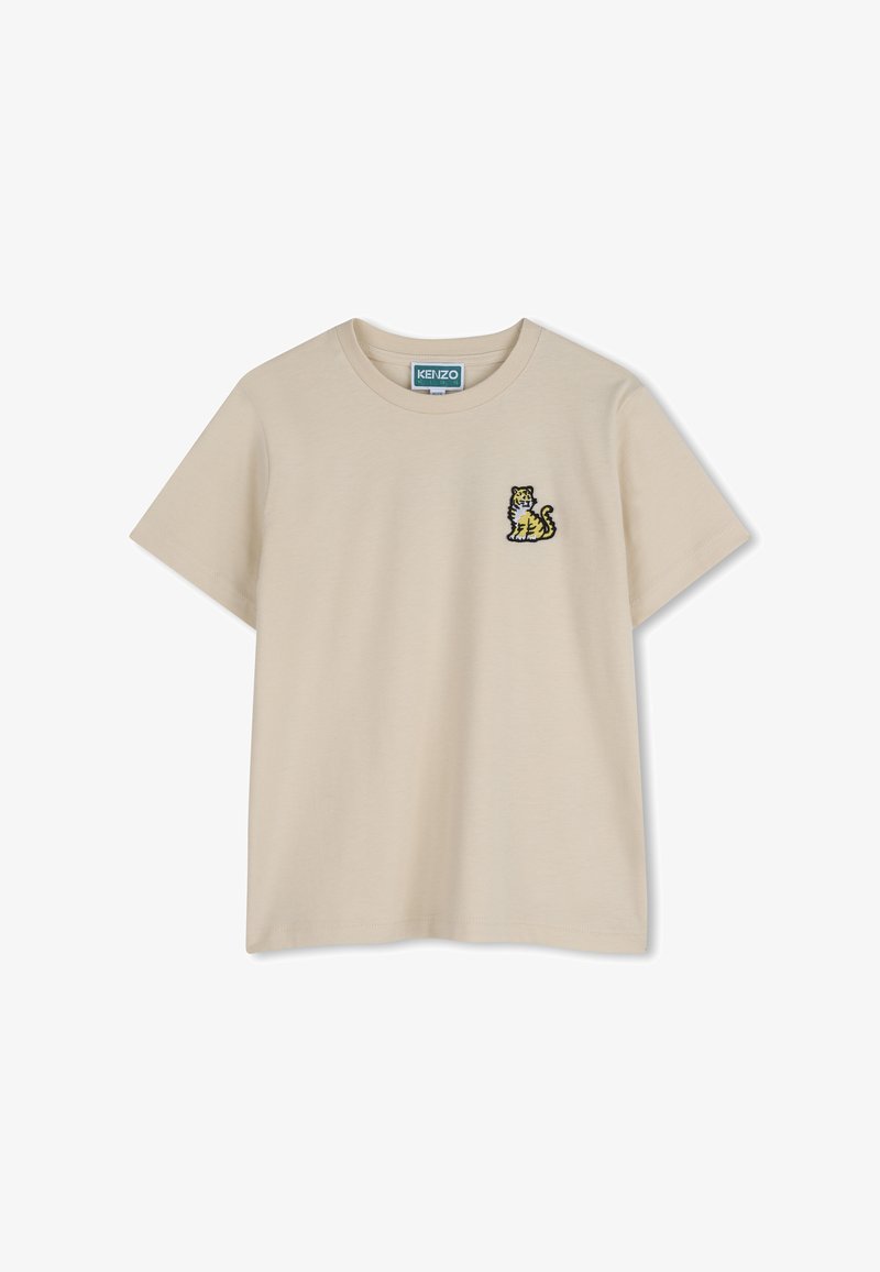T-shirt color beige in cotone con maniche corte, caratterizzata da un piccolo motivo ricamato a forma di tigre sul lato sinistro del petto.