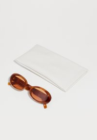Ovale solbriller med brunt farget glass og en blank brun ramme, ledsaget av et teksturert hvitt beskyttelsesetui.