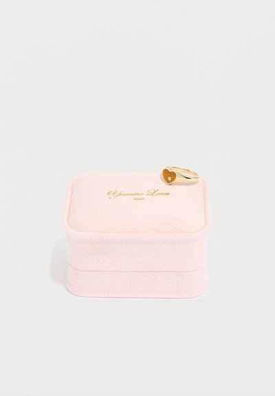 Ροζ βελουτέ κουτί κοσμημάτων με χρυσούς δακτυλίους σε σχήμα καρδιάς στην κορυφή, που διαθέτει μικρό διαμαντένιο διακοσμητικό. Το κουτί έχει μαλακή, υφή επιφάνεια.