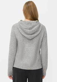 Sweat à capuche gris avec texture côtelée, manches longues et coupe décontractée. Dispose d'une large capuche et d'un ourlet arrière plus long.