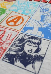 T-shirt en coton gris avec des graphismes de style bande dessinée. Les couleurs incluent rouge, bleu, vert, orange et jaune avec diverses illustrations de super-héros.