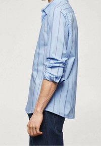 Camisa de manga larga azul claro con Rayas verticales en blanco y púrpura oscuro, con cuello abotonado y mangas remangadas.