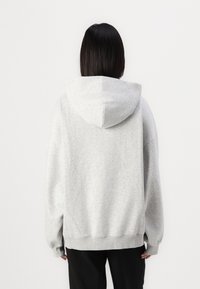 Grå hoodie lavet af blød stof, med en rummelig hætte og ribbet kant. Designet har en afslappet pasform og lange ærmer.
