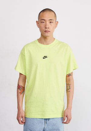 Neon yellow cotton t-shirt with a relaxed fit, featuring a small black Nike logo on the chest. Short sleeves and ribbed crew neckline.