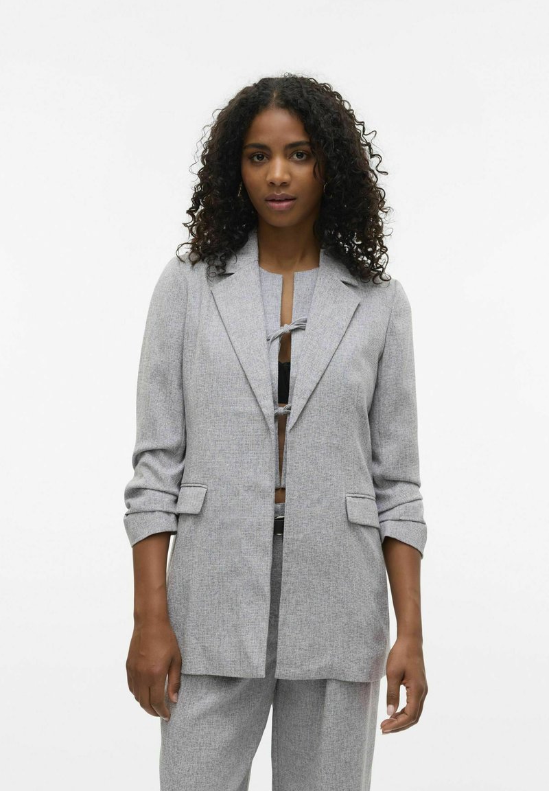 Blazer gris texturizado con solapas de muesca, cierre de botón y mangas arremangadas, combinado con una blusa a juego.