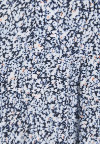 Modro-bílá vzorovaná tkanina s malými oranžovými akcenty; má texturovaný povrch a různé tvary v květinovém designu.