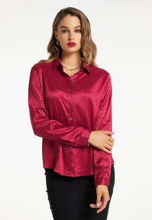 Satinbluse mit langen Ärmeln in tiefem Magenta und einem subtilen Animal-Print-Muster. Verfügt über eine Knopfleiste und einen klassischen Kragen. Strukturierte Oberfläche.