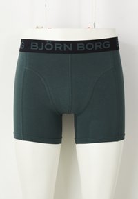 Sötét téglalap boxer alsónadrág, puha, rugalmas anyagból, fekete derékkal, amin a "BJÖRN BORG" logó és varrási részletek találhatók.
