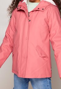 Rosa vattentät jacka gjord av ett slätt material, med en huva, två bröstfickor och en mjuk foder för värme.