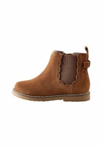 Bota de tobillo de ante marrón con bordes festoneados, paneles laterales elásticos y una pequeña lengüeta en la parte trasera. La suela de goma plana proporciona estabilidad.