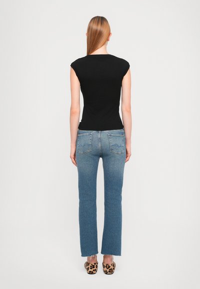 Black cap-sleeve top with fitted design, paired with light blue straight-leg jeans featuring a faded texture and frayed hems, worn with animal print shoes.