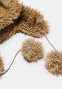 Brązowa tkanina z futra sztucznego z dwiema kulkami pomponowymi przymocowanymi sznurkami na białym tle.