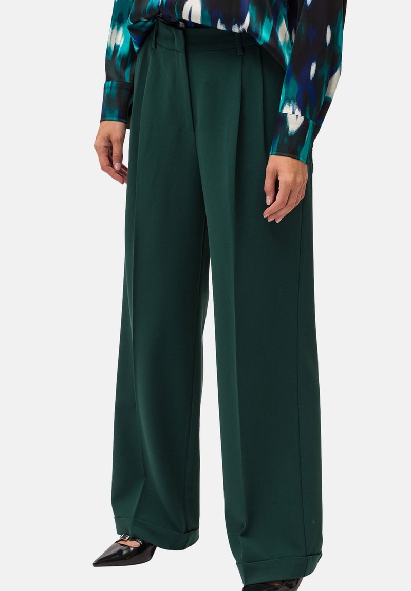 Pantaloni larghi verdi con pieghe, realizzati in tessuto morbido, con vita alta, tasche laterali e una vestibilità sartoriale.