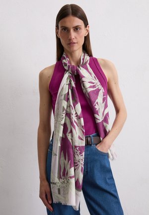 Purple floral scarf with green accents, lightweight fabric, draped around neck, contrasting with a fitted purple top and blue jeans.