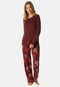 Conjunto de pijama burdeos que incluye una camiseta de manga larga con escote redondo y pantalones con estampado floral en tonos de rojo y rosa. Tejido suave de mezcla de algodón.