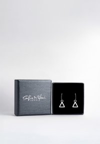 Scatola di gioielli nera aperta con logo bianco "Sofia Milani Jewels", contenente orecchini a cerchio in argento con piccoli pendenti a triangolo aperto all'interno.