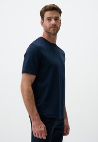 T-shirt in cotone blu navy con maniche corte, collo rotondo e una texture liscia. Presenta una vestibilità comoda e un design minimale.
