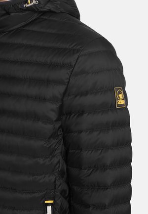 Giacca trapuntata nera con cuciture orizzontali, cappuccio con coulisse, tasca con cerniera e toppa del logo gialla sulla parte superiore del braccio.