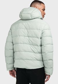 Hellgrüner Pufferjacke mit Kapuze, gestepptem Design und lässiger Passform, mit glatter Textur und elastischen Bündchen.