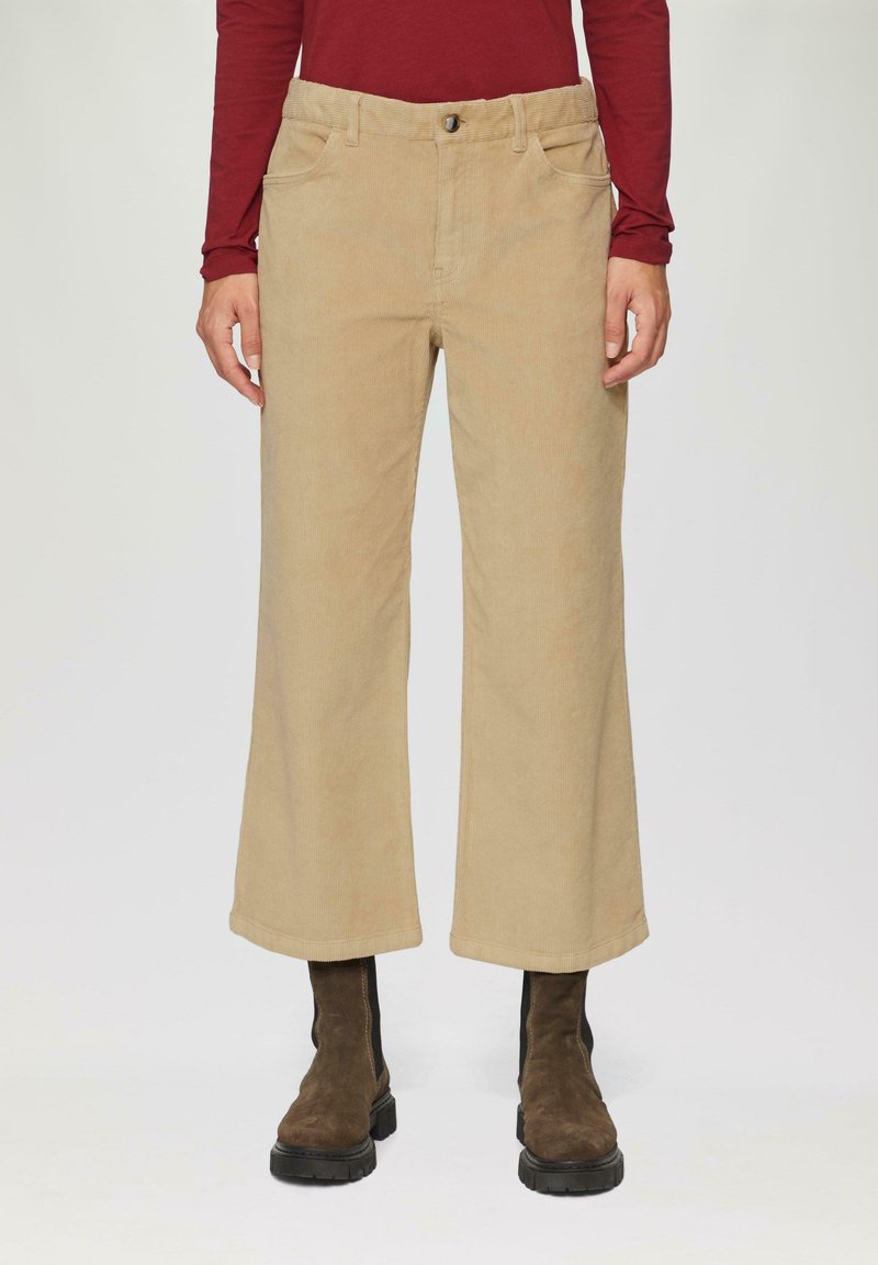 Beige corduroy wijde broek met knoopsluiting, voorzakken en een zachte textuur, aangevuld met bruine enkellaarsjes.