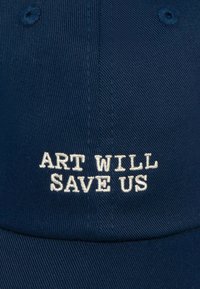 Marineblaue Baseballmütze aus strukturiertem Stoff mit cremefarbener, gestickter Aufschrift "KUNST WIRD UNS RETTEN" auf der Vorderseite.