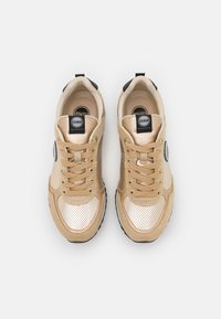 Sneaker beige con tomaia in mesh e dettagli in metallo dorato, logo rotondo e lacci piatti. Suola in gomma nera per una migliore aderenza.