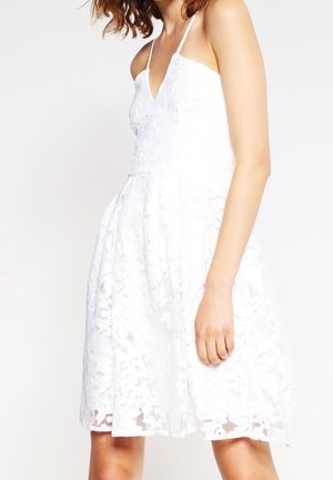 Witte kanten jurk met een V-hals en dunne bandjes, met bloemmotieven, nauwsluitend lijfje en uitlopende rok, gemaakt van lichtgewicht materiaal.