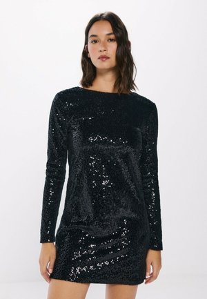 Schwarzes Pailletten-Mini-Kleid mit langen Ärmeln, rundem Halsausschnitt und figurbetonter Silhouette, das eine glänzende Textur und reflektierende Akzente aufweist.