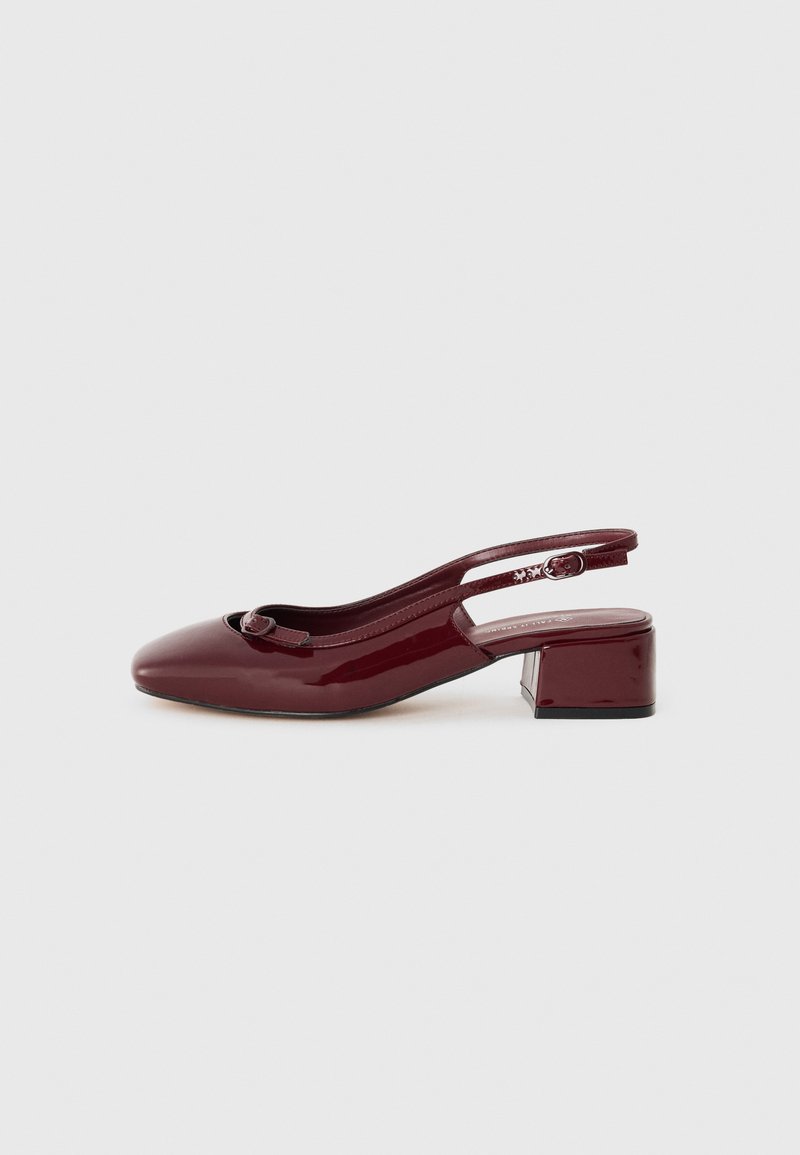 Chaussure à talon bas en cuir verni bordeaux, avec un bout carré, un petit talon carré et un détail de nœud décoratif sur la sangle avant.