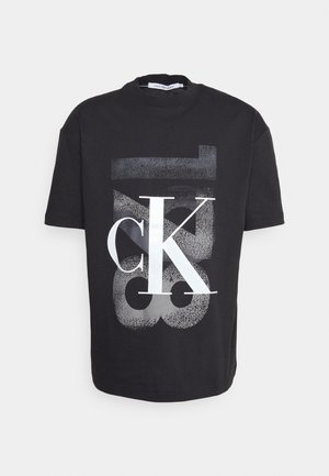 Schwarzes T-Shirt mit kurzen Ärmeln und Rundhalsausschnitt, vorne mit großem weißem und grauem "cK" und "Jeans" Schriftzug und innen am Kragen mit "Calvin Klein Jeans" Label.