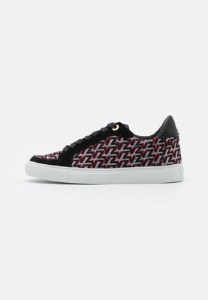Niskie sneakersy z czarno-czerwono-białym geometrycznym wzorem, czarnymi zamszowymi akcentami, czarnymi sznurówkami i białą gumową podeszwą.