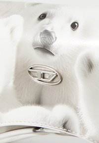 Sac à main blanc avec un motif d'ours polaire et une texture de fourrure fine. Accent en métal argenté avec détail du logo. Surface lisse et brillante.