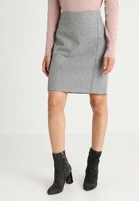 Grå blyertskjol med en mjuk textur och sidsömmar. I kombination med svarta mockastövlar och en ljusrosa tröja.