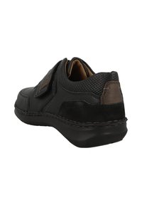 Chaussure en cuir noir avec un panneau en maille texturée, des accents bruns et une semelle en caoutchouc robuste. Dotée d'une sangle à crochet et boucle pour une fermeture facile.