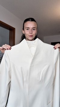 Witte getailleerde jas met een hoge kraag, gestructureerde schouders en voornaaddetails. Gladde stof, met een minimalistisch ontwerp.