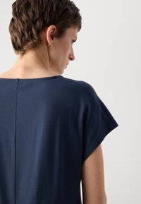 Navy blue short-sleeve top featuring a wide neckline and a subtle back seam, made from soft, smooth fabric with a relaxed fit.