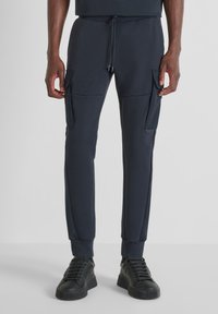 Marine joggerbroek van zachte stof, voorzien van cargozakken, een trekkoord in de taille en geribbelde boorden. Gepaard met zwarte sneakers.