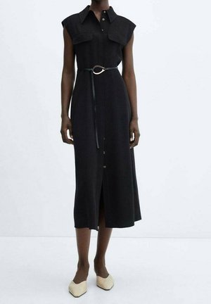 Robe midi noire sans manches avec boutons sur le devant, grandes poches poitrine, ceinture fine avec boucle métallique, portée avec des ballerines pointues beiges.