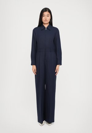 Navy blue jumpsuit with a collared neckline and a front zipper. Features long sleeves and a fitted waist, made from smooth, lightweight fabric.