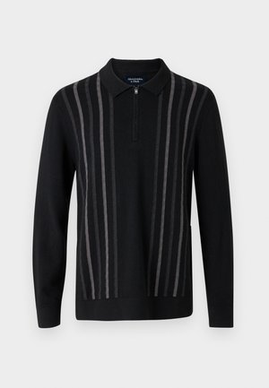 Schwarzer Pullover mit Reißverschlusskragen, mit vertikalen grauen Streifen, aus weichem Strickstoff, mit langen Ärmeln und seitlichen Schlitzen.