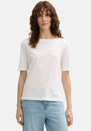 Witte short-sleeve shirt met een licht bootnek. Zacht, lichtgewicht stof. Gecombineerd met lichtblauwe denim jeans.