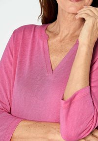 Rosa V-Ausschnitt-Oberteil mit Dreiviertelärmeln, weichem Stofftextur, mit einer gewellten Ausschnitt und bequemer Passform.