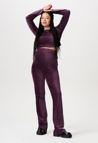 Ensemble en velours violet composé d'un haut crop à manches longues et d'un pantalon évasé. Tissu texturé avec une finition douce et une silhouette ajustée.